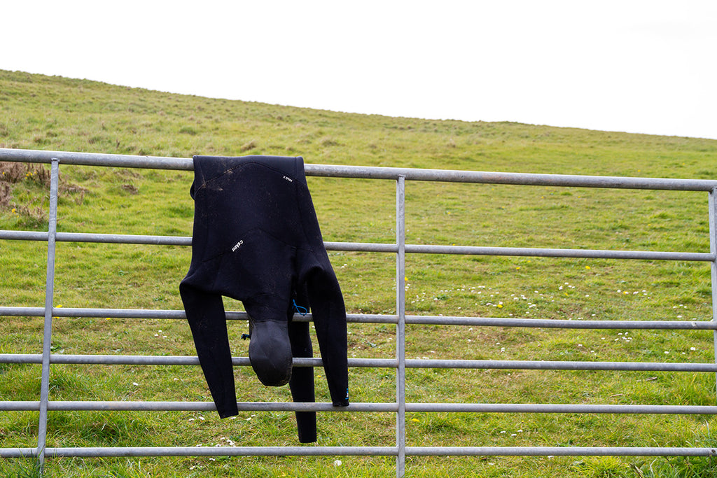 a wetsuit hanging to dry over a gate