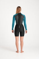 Beth wearing a black and teal spring wetsuit on a white background